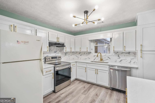 kitchen featuring appliances with stainless steel finishes, light countertops, under cabinet range hood, white cabinetry, and a sink