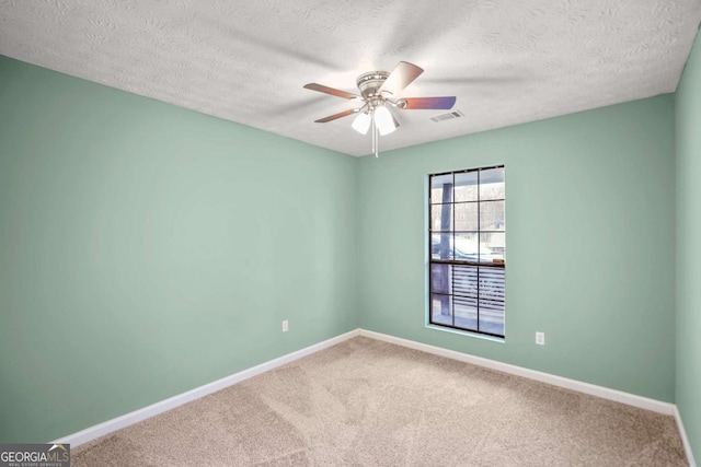 carpeted spare room with a ceiling fan, visible vents, a textured ceiling, and baseboards