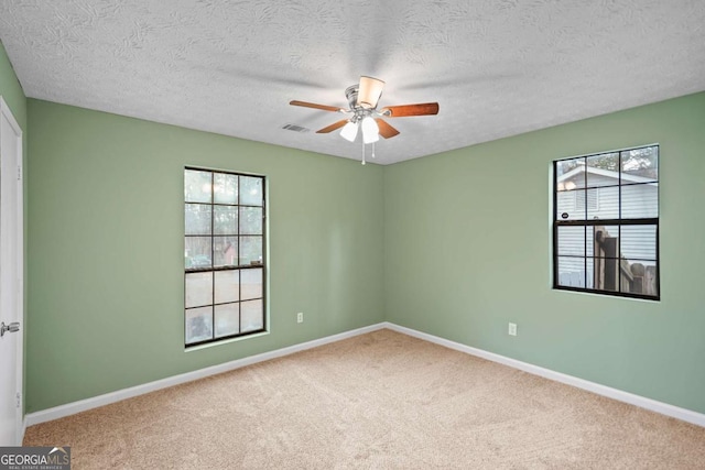 empty room with visible vents, baseboards, a ceiling fan, carpet, and a textured ceiling