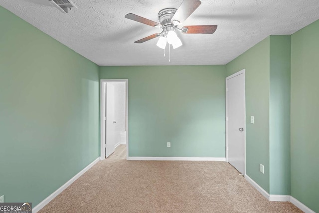 unfurnished room featuring carpet floors, a ceiling fan, visible vents, and baseboards