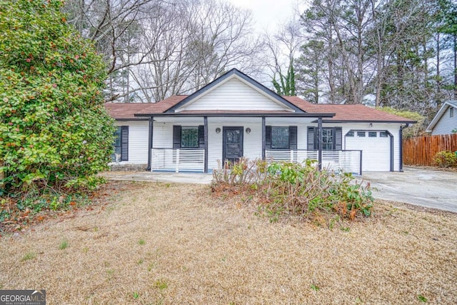 view of front of home with covered porch, driveway, an attached garage, and fence