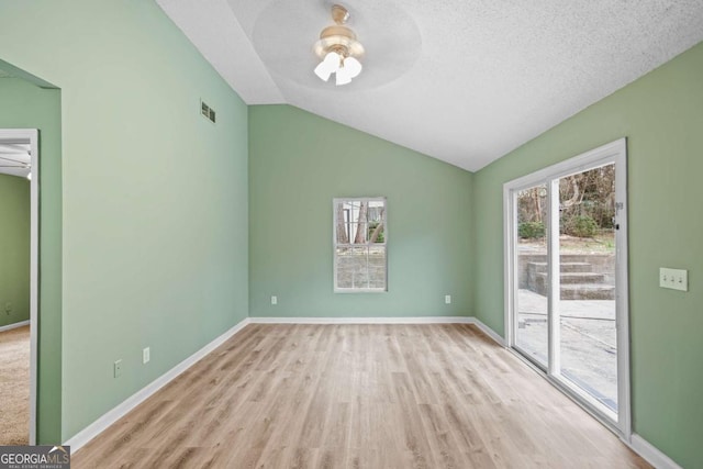 empty room featuring baseboards, visible vents, a ceiling fan, lofted ceiling, and wood finished floors