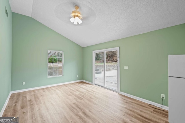 interior space featuring lofted ceiling, visible vents, a textured ceiling, wood finished floors, and baseboards