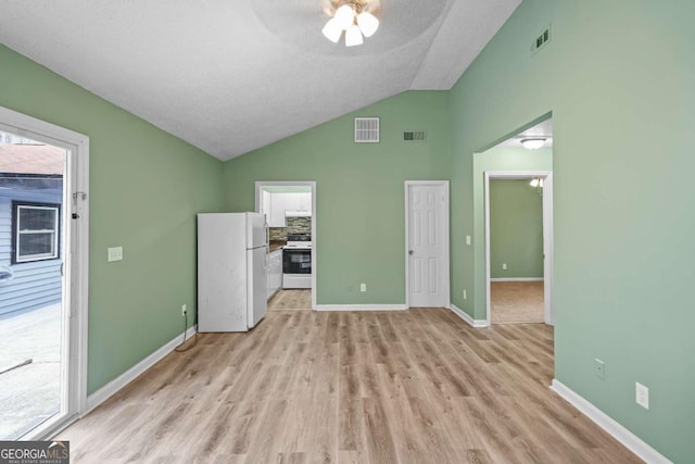 unfurnished bedroom featuring visible vents, vaulted ceiling, freestanding refrigerator, and light wood-style floors