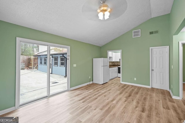 interior space featuring light wood-type flooring, visible vents, and lofted ceiling