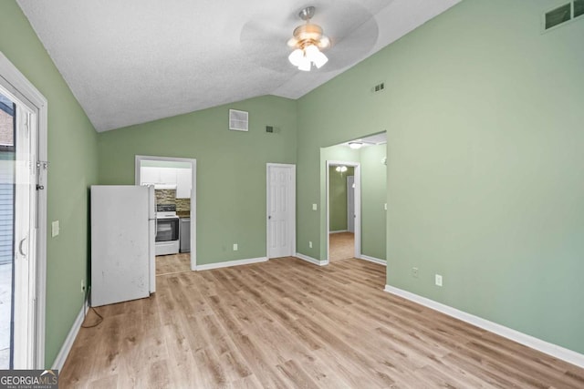 unfurnished bedroom with light wood-style floors, visible vents, and freestanding refrigerator