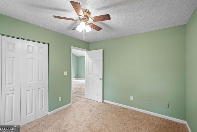 unfurnished bedroom featuring carpet, a closet, a textured ceiling, and baseboards