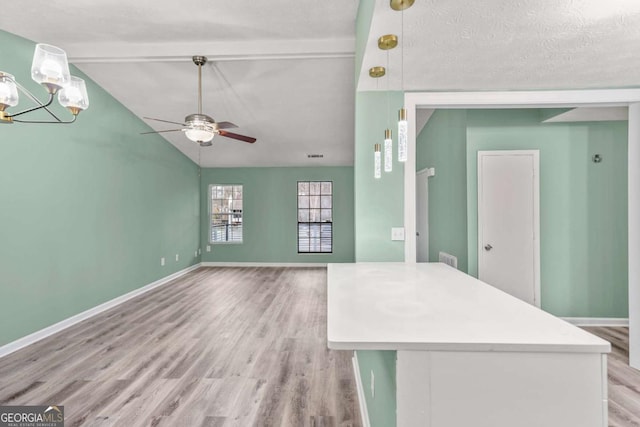 interior space with lofted ceiling with beams, ceiling fan with notable chandelier, visible vents, baseboards, and light wood finished floors