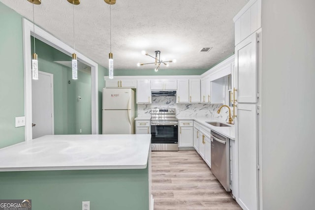 kitchen featuring stainless steel appliances, white cabinets, a sink, light wood-type flooring, and under cabinet range hood