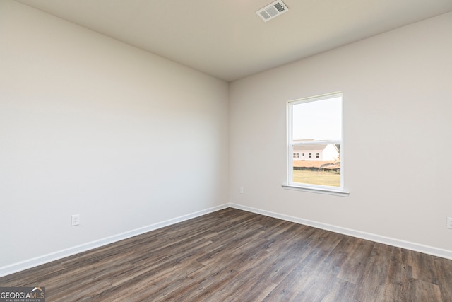 unfurnished room featuring baseboards, visible vents, and dark wood finished floors