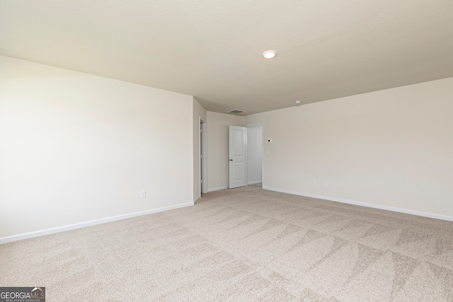 spare room featuring light carpet and baseboards