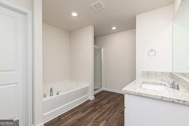 full bath with a stall shower, visible vents, wood finished floors, a garden tub, and vanity