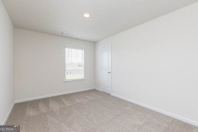 spare room with light carpet, visible vents, and baseboards