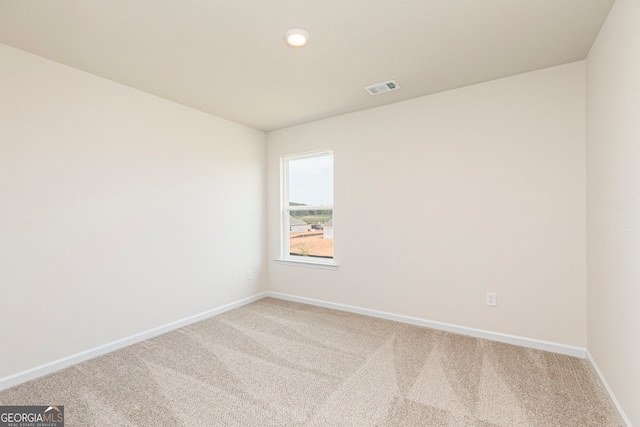 unfurnished room with carpet floors, visible vents, and baseboards