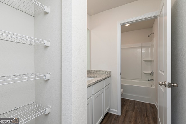 bathroom with toilet, shower / washtub combination, wood finished floors, and vanity