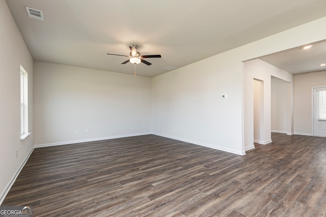 empty room with a ceiling fan, dark wood-style flooring, visible vents, and baseboards