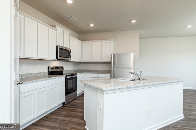 kitchen with a sink, visible vents, appliances with stainless steel finishes, dark wood-style floors, and an island with sink