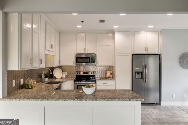 kitchen with stainless steel appliances, stone counters, a sink, and visible vents