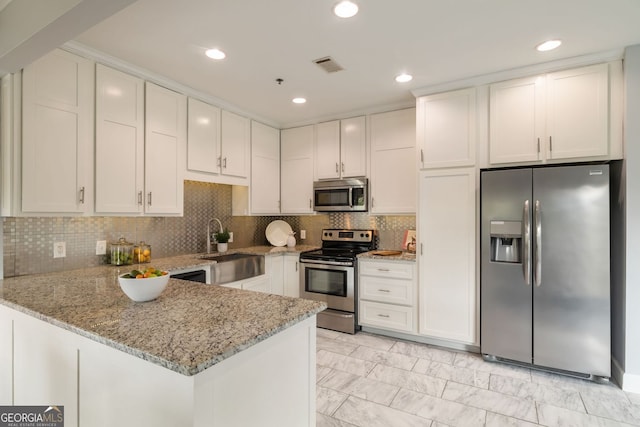 kitchen with light stone counters, a peninsula, visible vents, marble finish floor, and appliances with stainless steel finishes