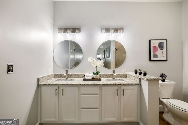 bathroom featuring double vanity, a sink, and toilet