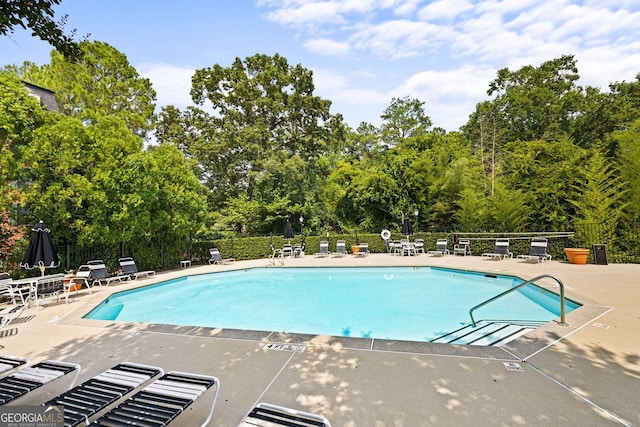 pool with a patio area and fence