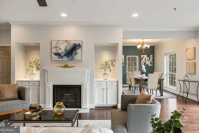 living room featuring ornamental molding, dark wood-style flooring, a fireplace, a chandelier, and recessed lighting