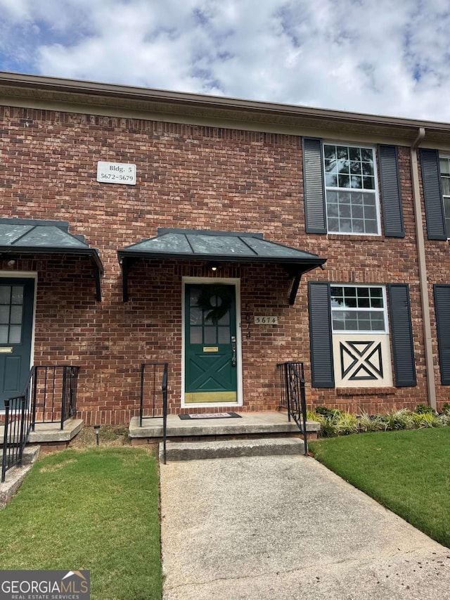 view of front of house featuring brick siding and a front lawn