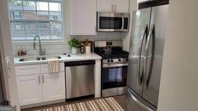 kitchen with a sink, decorative backsplash, light countertops, white cabinets, and appliances with stainless steel finishes