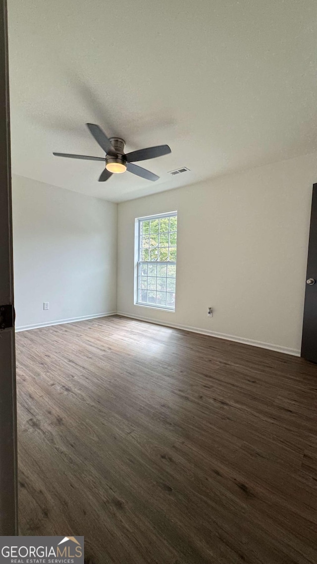 unfurnished room with visible vents, baseboards, wood finished floors, and a ceiling fan