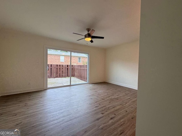 empty room with dark wood finished floors, baseboards, and a ceiling fan