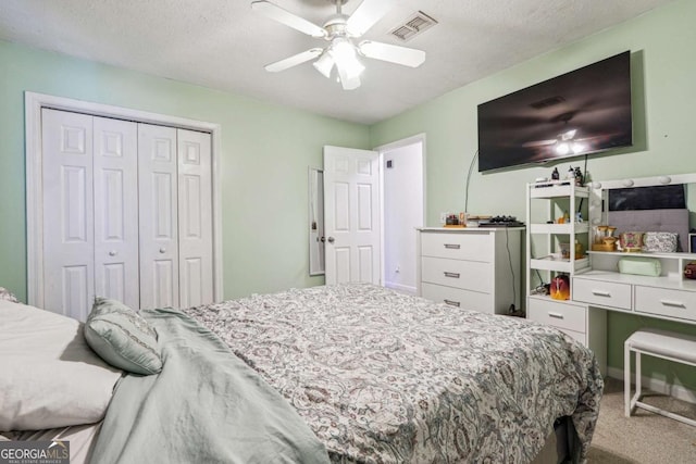 carpeted bedroom featuring ceiling fan, a textured ceiling, visible vents, and a closet