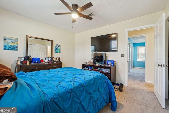 bedroom with a textured ceiling, carpet floors, a ceiling fan, visible vents, and baseboards