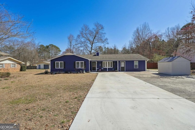 ranch-style house with an outbuilding, driveway, a shed, board and batten siding, and a front yard