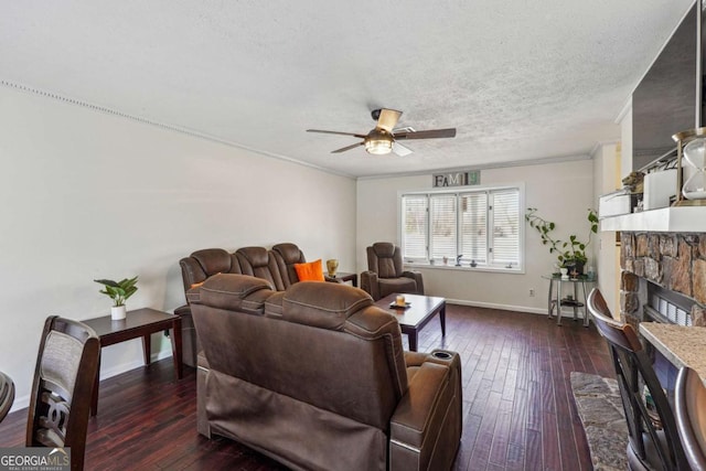 living room with dark wood-type flooring, a fireplace, a textured ceiling, and ornamental molding