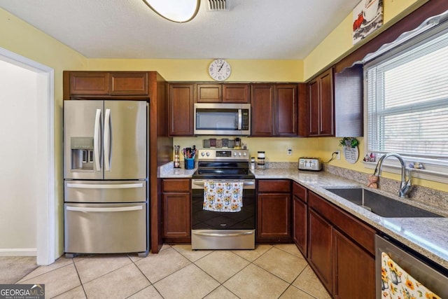 kitchen with light tile patterned floors, light countertops, appliances with stainless steel finishes, and a sink