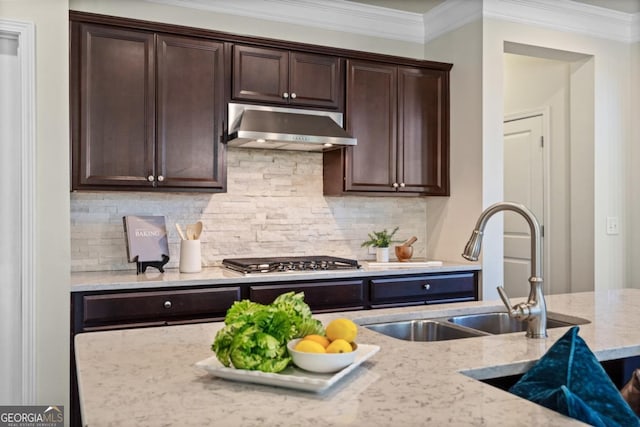 kitchen featuring under cabinet range hood, dark brown cabinetry, stainless steel gas cooktop, light stone counters, and a sink