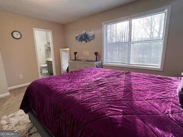 bedroom featuring ensuite bathroom, carpet floors, and baseboards