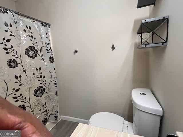 full bathroom with a shower with shower curtain, baseboards, toilet, and wood finished floors