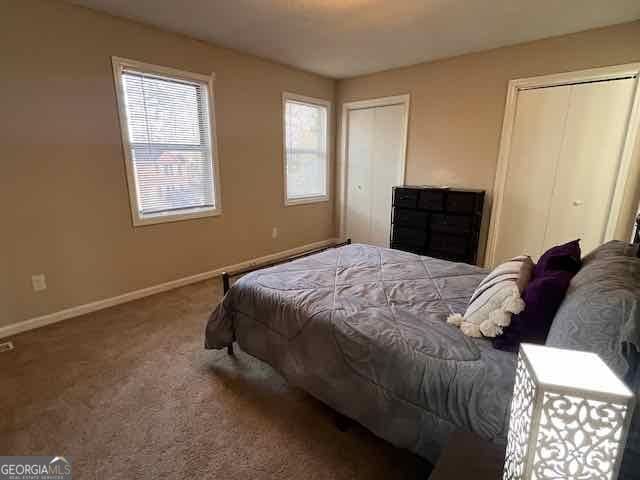 bedroom featuring baseboards, carpet, and multiple closets