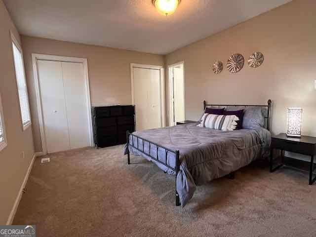 carpeted bedroom with baseboards and two closets