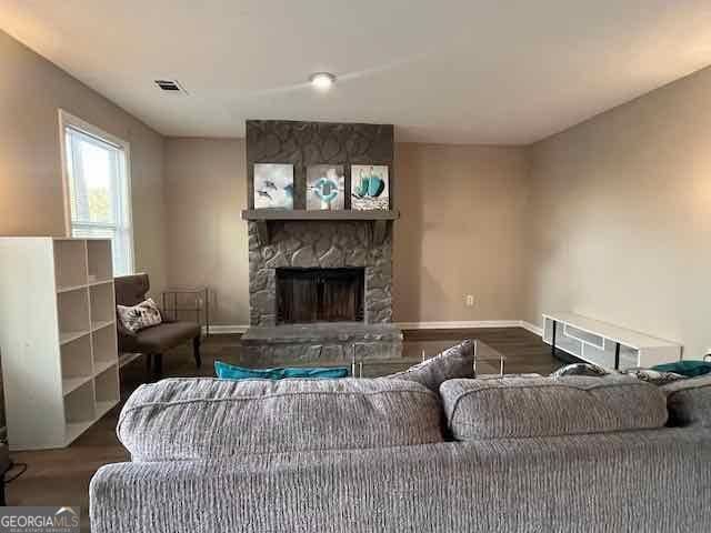 living area featuring visible vents, a fireplace, baseboards, and wood finished floors