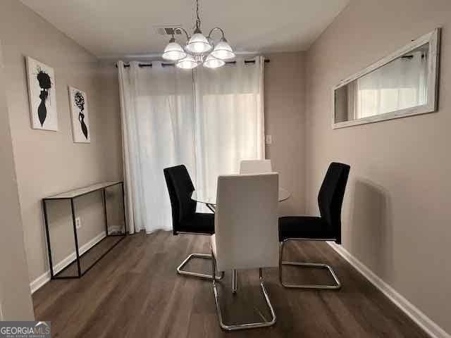 dining space featuring a notable chandelier, baseboards, visible vents, and wood finished floors