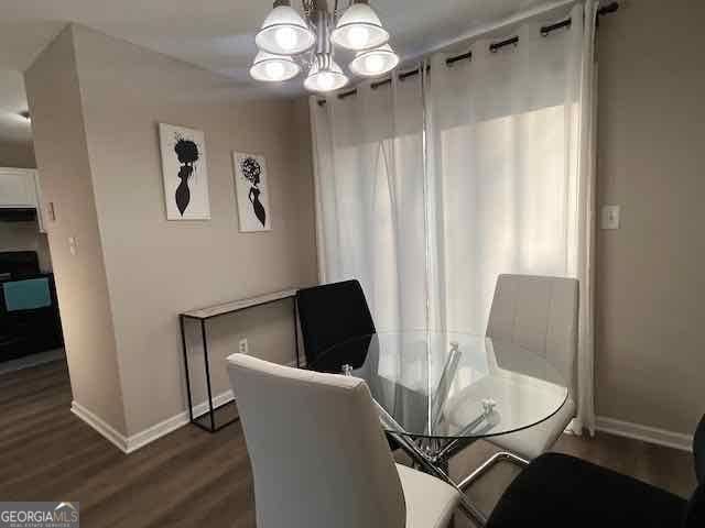 dining room with an inviting chandelier, baseboards, and dark wood-type flooring