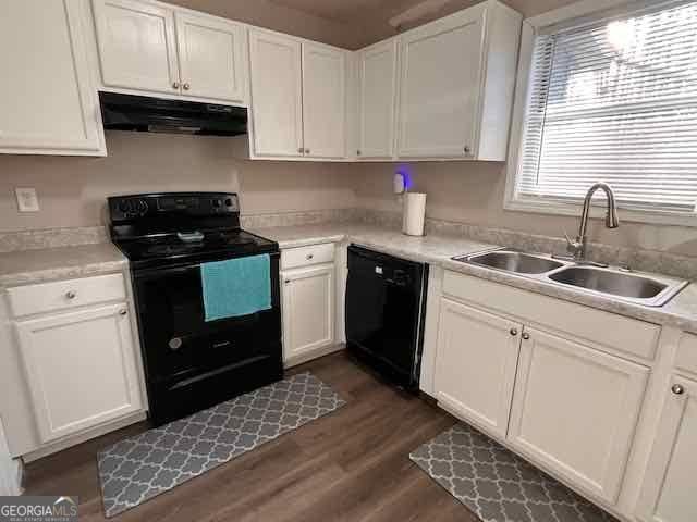 kitchen featuring white cabinets, a sink, under cabinet range hood, and black appliances