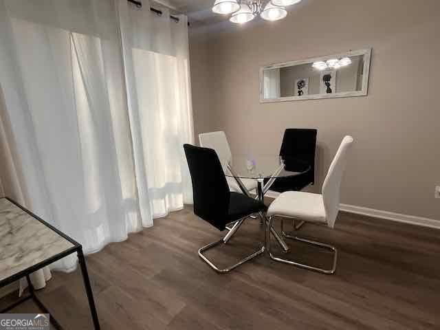 dining area with a chandelier, wood finished floors, and baseboards