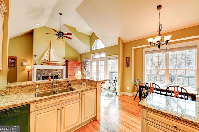 kitchen featuring french doors, a fireplace, light wood finished floors, a sink, and dishwasher