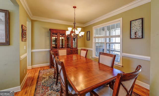 dining room with a chandelier, ornamental molding, light wood finished floors, and baseboards