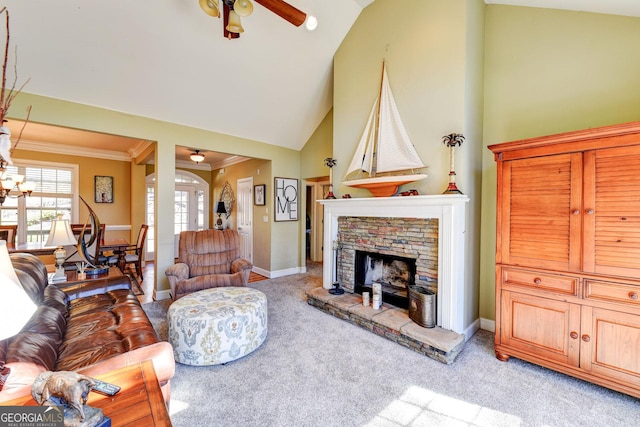 living area with light carpet, ornamental molding, a stone fireplace, high vaulted ceiling, and ceiling fan with notable chandelier