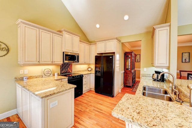 kitchen featuring a peninsula, a sink, cream cabinetry, black appliances, and light wood finished floors