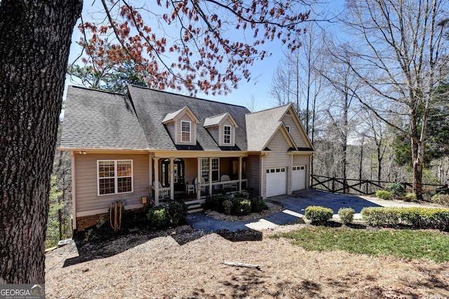 cape cod house with a shingled roof, covered porch, an attached garage, fence, and driveway